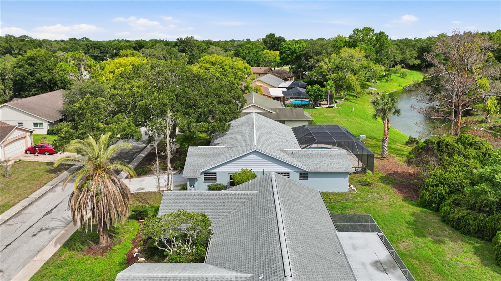 Rear aerial view highlighting the screened pool area and peaceful waterfront surroundings.