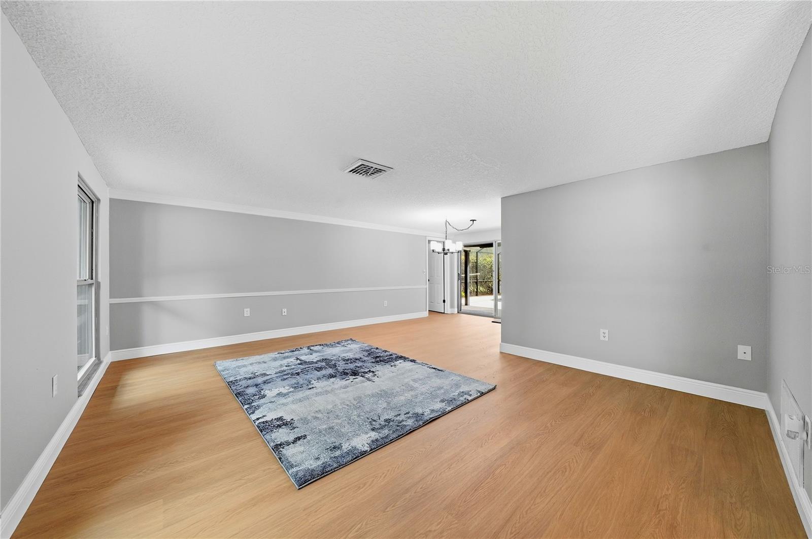 Expansive main living area featuring new flooring, fresh paint, crown molding, and an open, flexible layout.