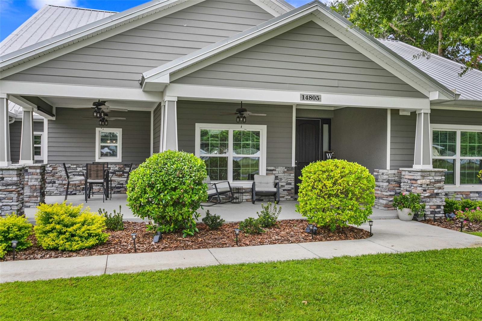 Inviting covered front porch featuring stacked stone accents, durable Hardie siding, and a welcoming entry that showcases the home's custom craftsmanship and curb appeal.