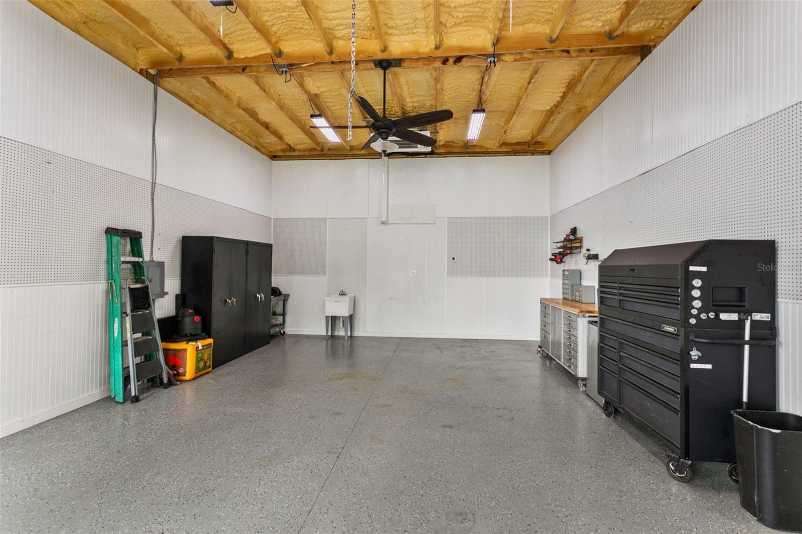 Climate-controlled detached workshop/RV garage featuring epoxy floors, spray foam insulation, LED lighting, ceiling fan, utility sink, extensive pegboard storage, and premium workspace—ideal for RV storage, car enthusiasts, hobbies, or a home workshop.