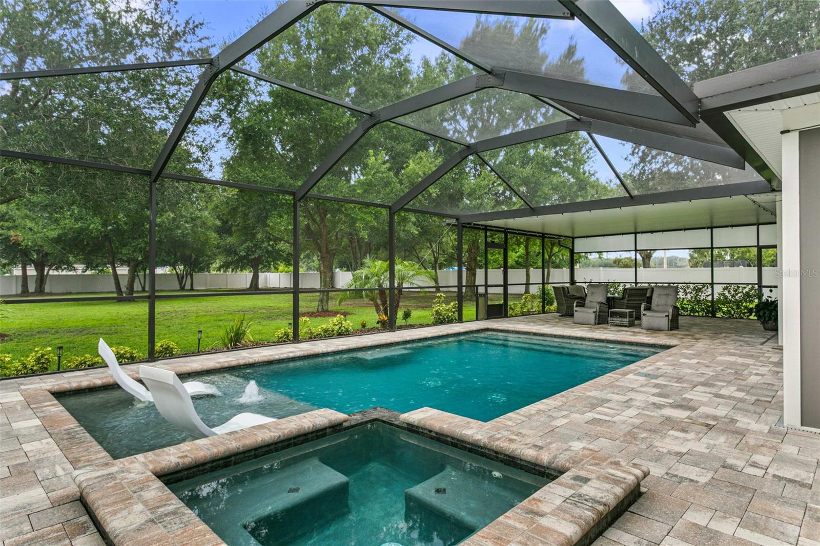 Beautiful backyard oasis with multiple seating areas and lush landscaping.